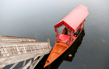 Rumah perahu kayu tradisional dan shikara berlayar di Danau Dal, Srinagar, dengan latar pegunungan Himalaya yang memukau
